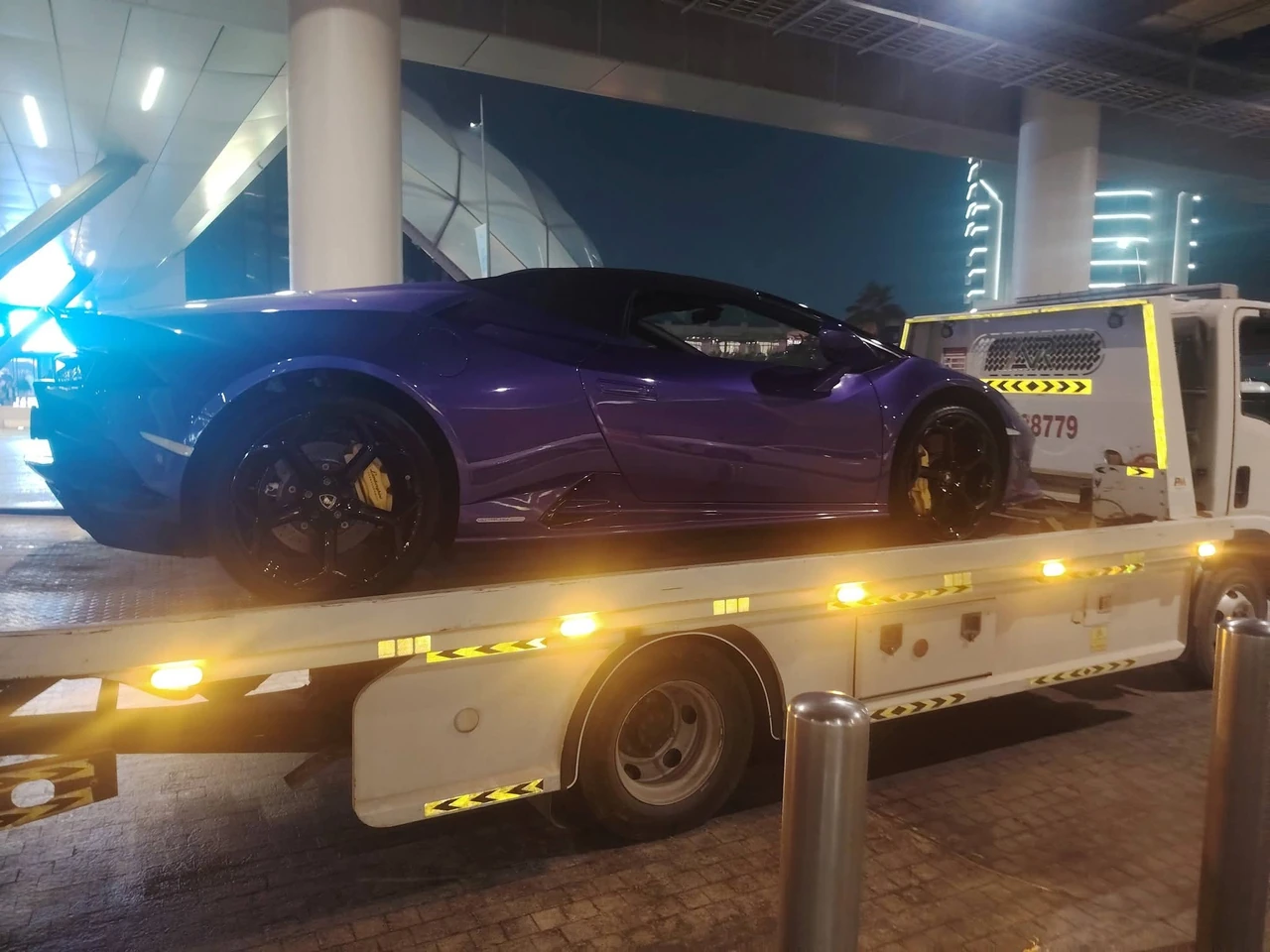 Flatbed recovery truck carrying a vehicle at night