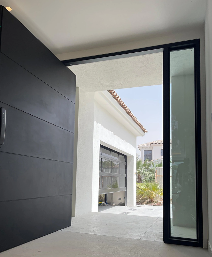 A broad dark pivot entrance shown with surrounding glazing.