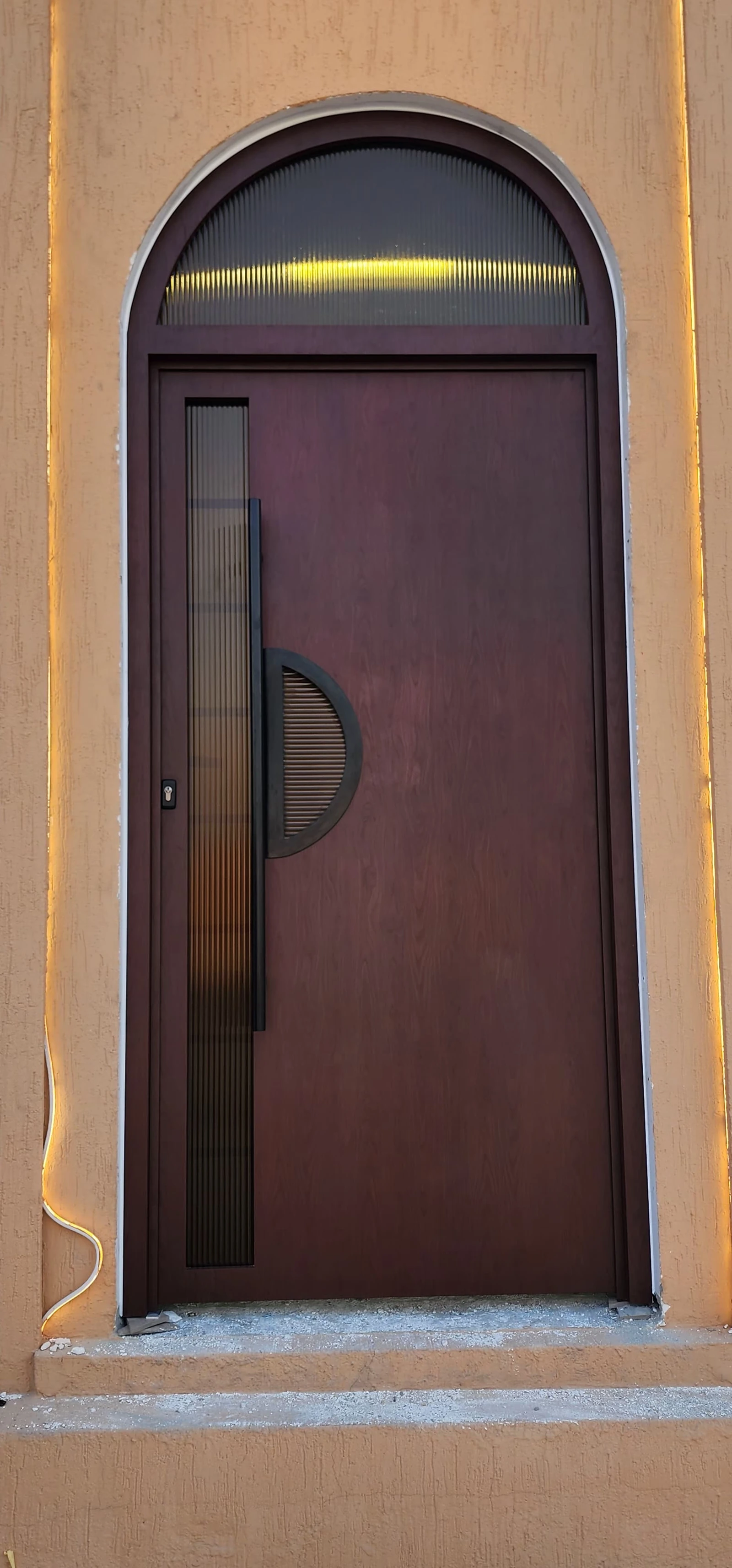 A dark entrance door with a pointed arch and glazed upper panel.