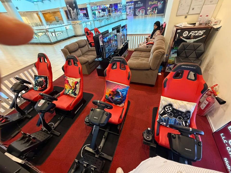 PS Game Drive racing seats with steering wheels and pedals, beside the console lounge